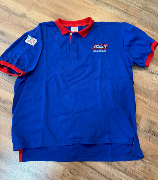 Blue polo shirt with red accents on a wooden floor